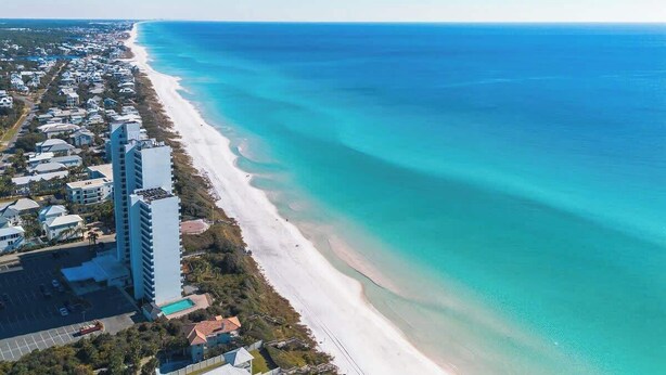 A coastal hotel with a beach view, a parking lot, and a large building with multiple floors. - Coast & Key Cottage by Stay on 30a (Seagrove Beach)