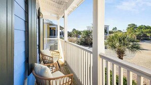 A balcony with wicker chairs and a view of a street and greenery. - Coast & Key Cottage by Stay on 30a (Seagrove Beach)