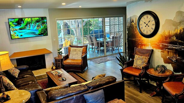 Ein Wohnzimmer mit Kamin, Ledersofas, Fernseher und einer großen Wanduhr.