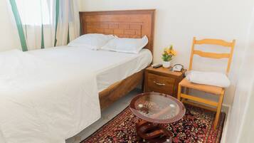 Relax in a cozy space with a comfortable bed, bedside table, and plush chair.