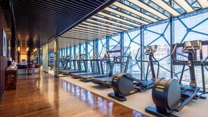 A gym with treadmills and elliptical machines, large windows, and a wooden floor. - Gloria Plaza Hotel Dongsheng (Beijing)
