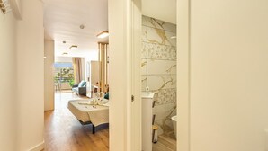 Une chambre d’hôtel avec un lit, une salle de bain carrelée de marbre et une vue sur l’extérieur.