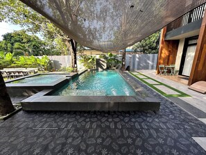 Una piscina con una pérgola en la parte superior, rodeada por un patio con mobiliario exterior.