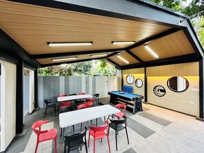 Un patio exterior con mesas y sillas, una mesa de billar y una pared con espejos circulares.