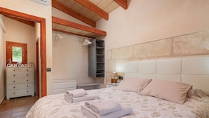A bedroom with a bed, a dresser, a mirror, a wardrobe, and a hanging rack. - CAN GARDO - Villa with private pool and Free Wifi (Pollença)