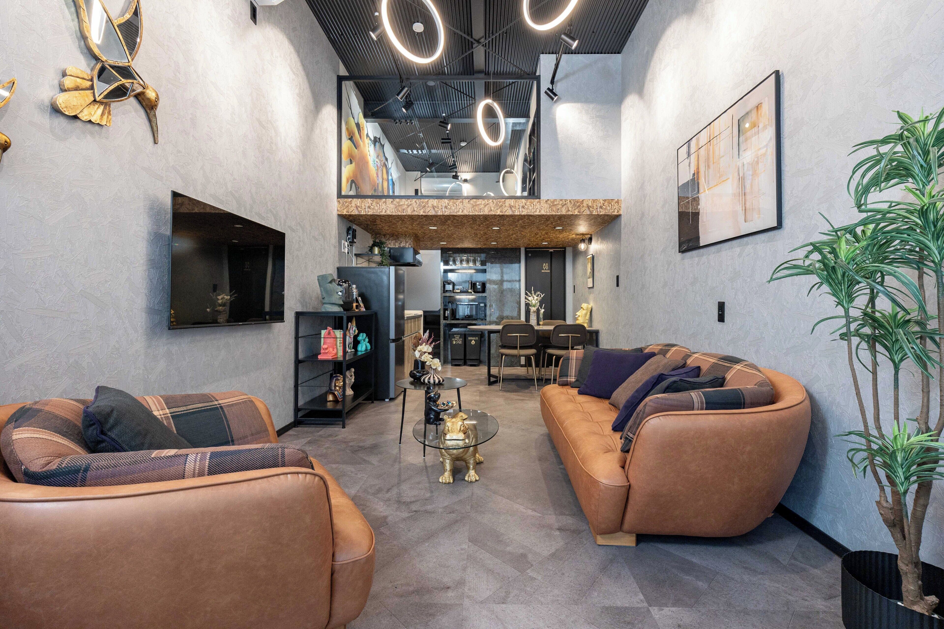 Un espace de vie moderne avec des canapés en cuir, une table basse et, au fond, un coin repas.