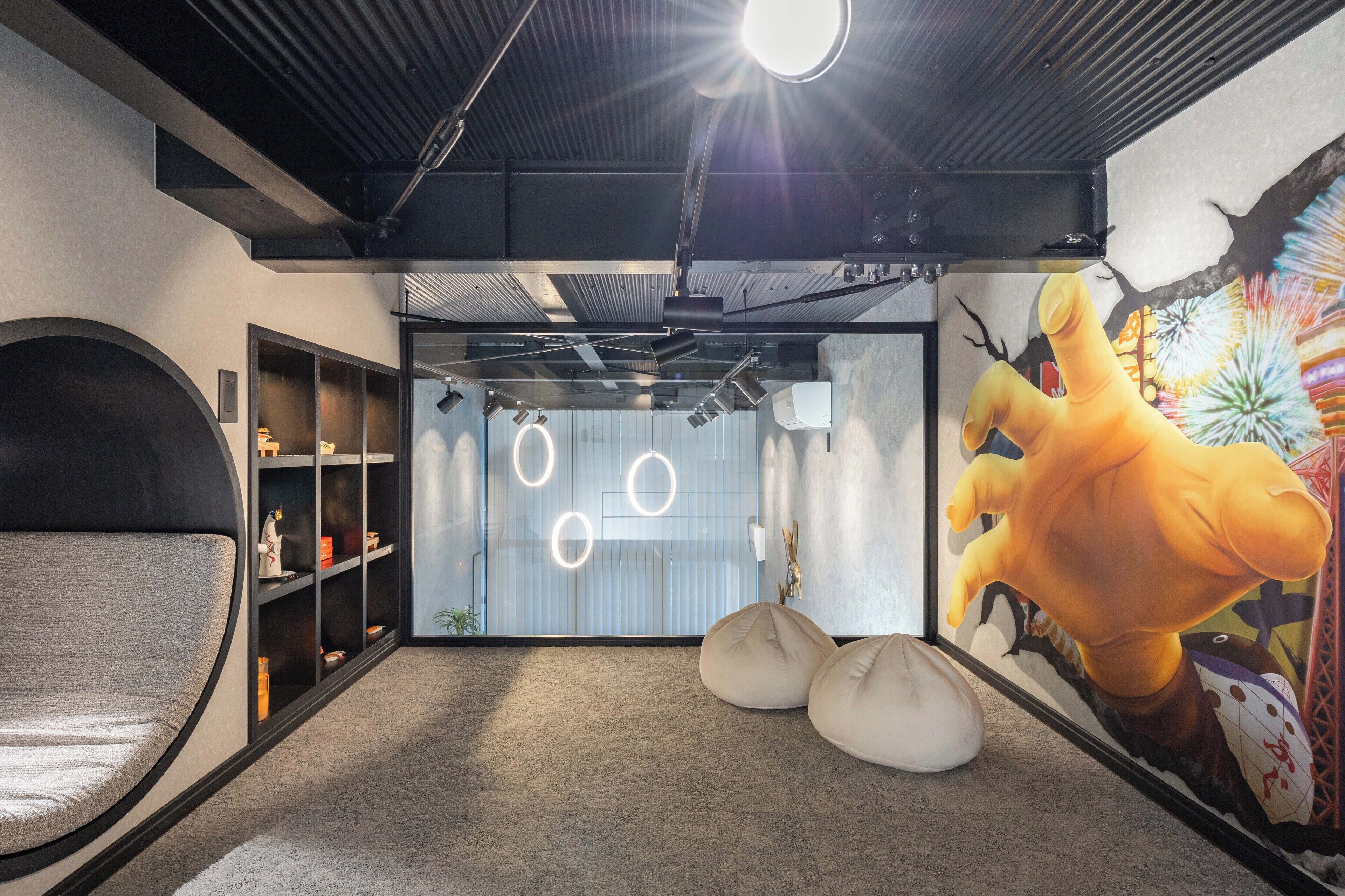 Un intérieur moderne agrémenté d’un grand luminaire circulaire, d’une fresque représentant un personnage de dessin animé et d’un espace détente avec des fauteuils en forme de poire.