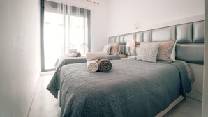 A modern bedroom with a large bed, two bedside tables, and a window with sheer curtains. - Luxury Duplex Infinity Pool - EHHouse (Estepona)