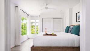 Ein modernes Schlafzimmer mit einem großen Bett, einem Deckenventilator und einem Fenster mit Vorhängen.