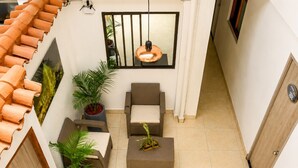 A compact living space with a tiled floor, a sofa, a small table, and potted plants. - Sol de Estadio (Medellín)