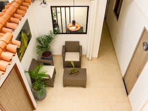 A compact living space with a tiled floor, a sofa, a small table, and potted plants. - Sol de Estadio (Medellín)