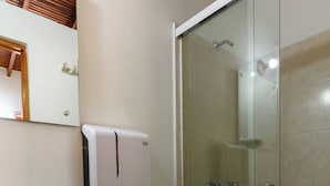 Casa de banho com sanita, lavatório e cabine de duche de vidro.