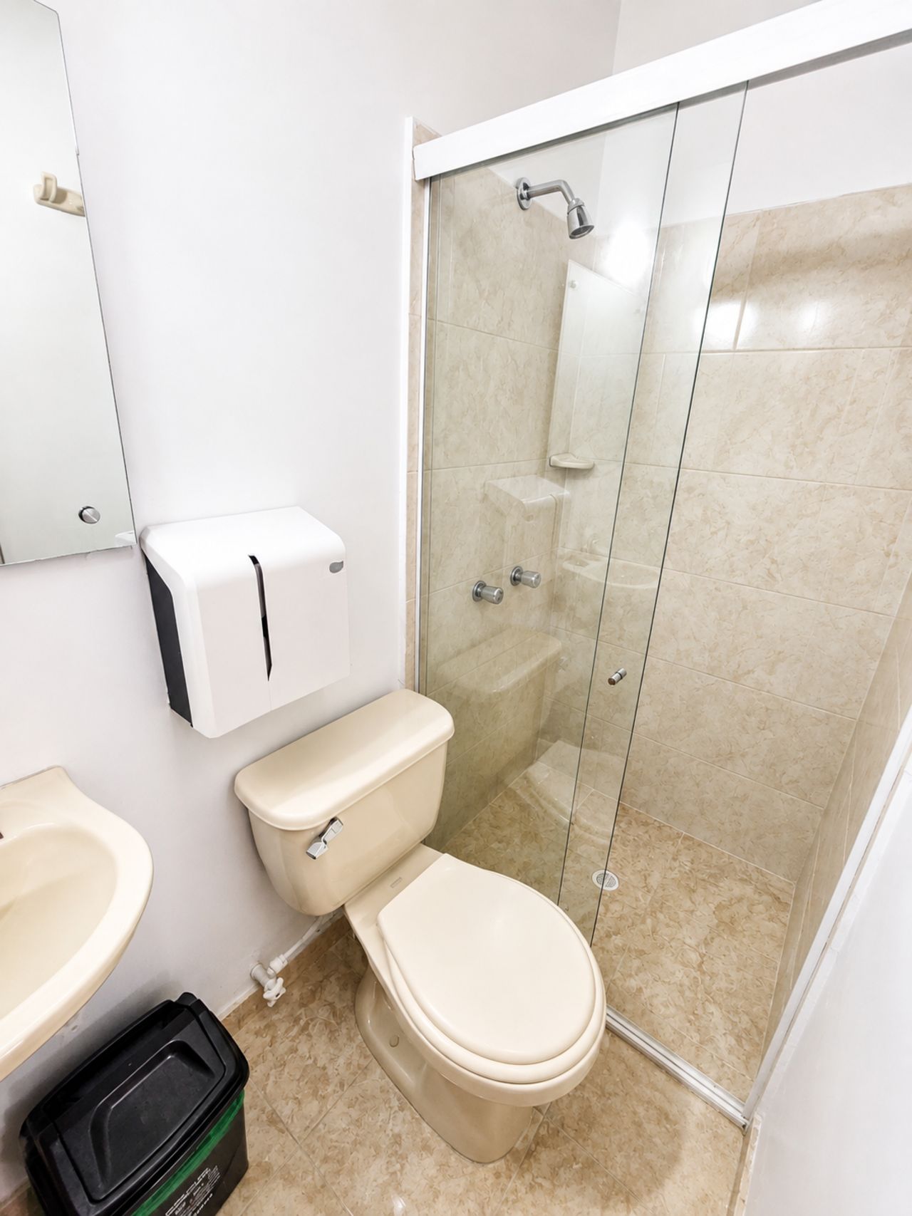 A bathroom with a toilet, a sink, and a glass-enclosed shower area.