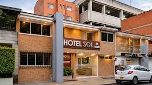 A hotel with a prominent sign, a visible entrance, and a parked car. - Sol de Estadio (Medellín)
