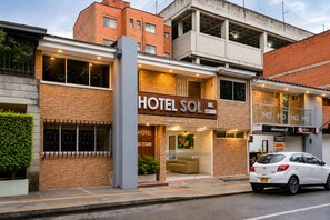 A hotel with a prominent sign, a visible entrance, and a parked car. - Sol de Estadio (Medellín)
