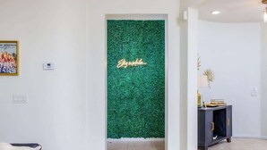 A hallway with a green textured wall, a framed picture, and a dark-colored console table. - Stylish Indio Sanctuary with Heated Pool (Indio)