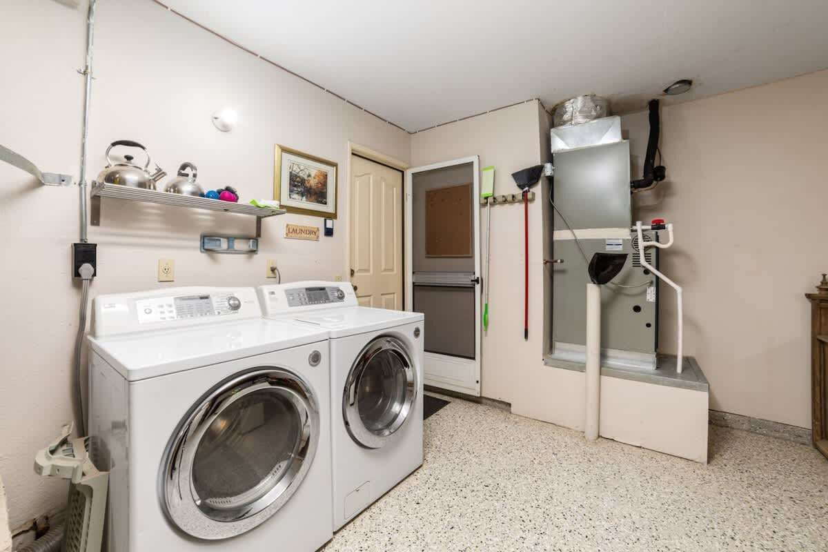 A laundry area with two front-loading washing machines, a dryer, and a utility room with a water heater and a vent.