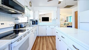 A modern kitchen with white cabinets, a built-in oven, and a microwave.