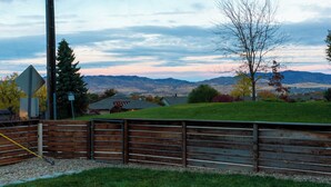 A rural landscape with a wooden fence, a bike lane sign, and houses in the background.