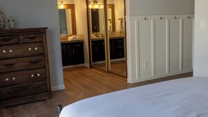 A bedroom with a wooden dresser, a large mirror, and a bed.