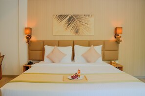 A hotel room with a large bed, two bedside lamps, a nightstand, and a wall-mounted artwork. - Cocomo Maldives (Himmafushi)