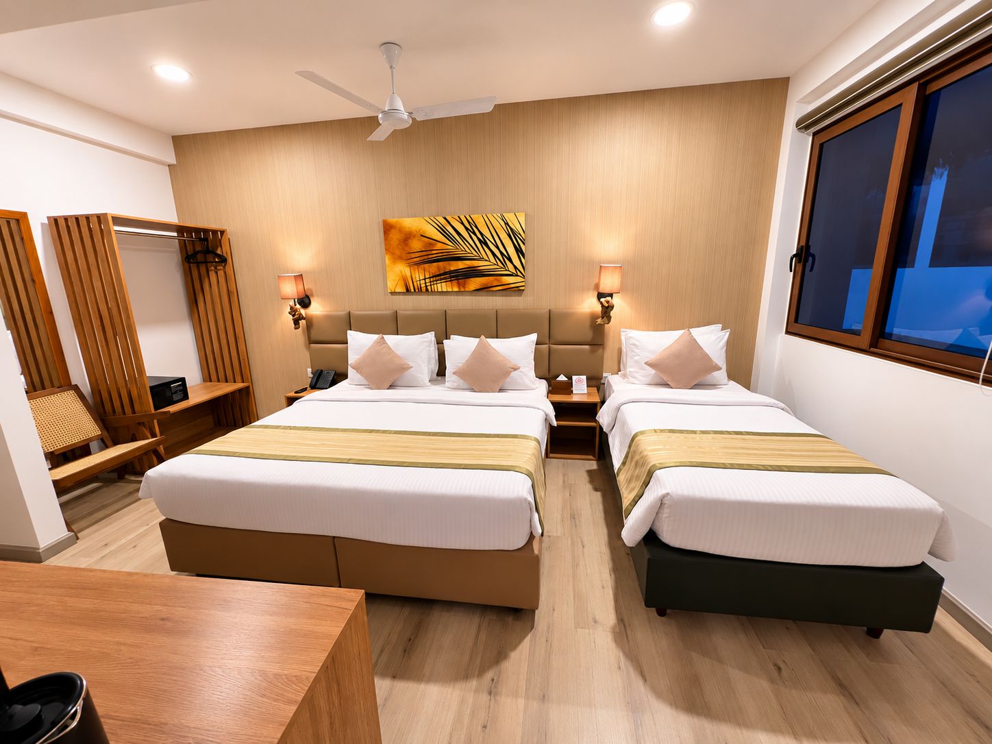 Habitación de hotel con dos camas, un ventilador de techo, un cuadro y una ventana.