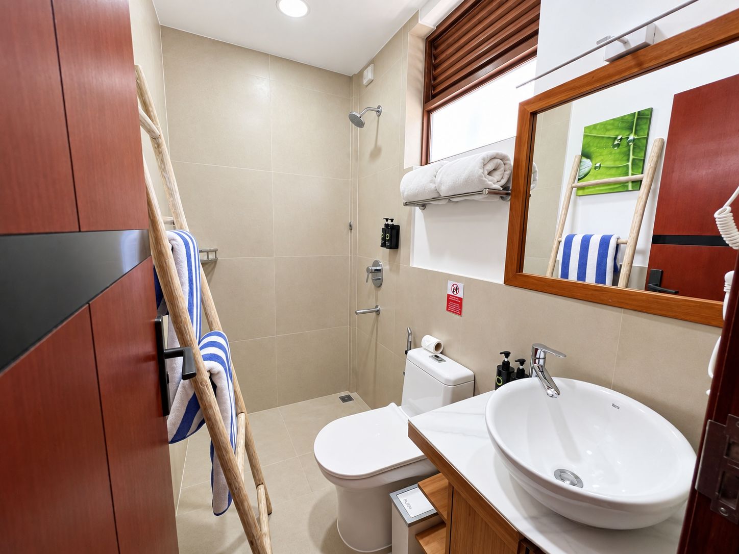 Un baño con inodoro, lavamanos, ducha y un perchero para toallas.
