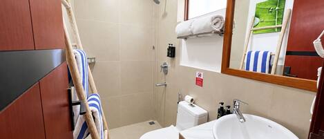 Un baño con inodoro, lavamanos, ducha y un perchero para toallas.