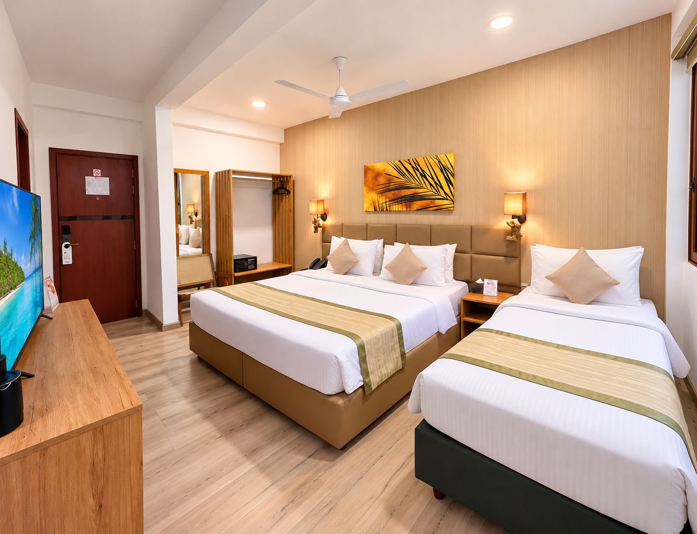 A hotel room with two beds, a desk, a TV, and a ceiling fan.