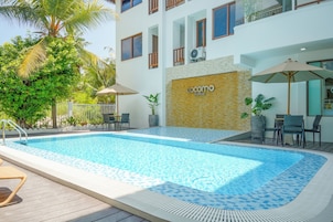 Una piscina al aire libre, sombrillas, sillones reclinables de piscina