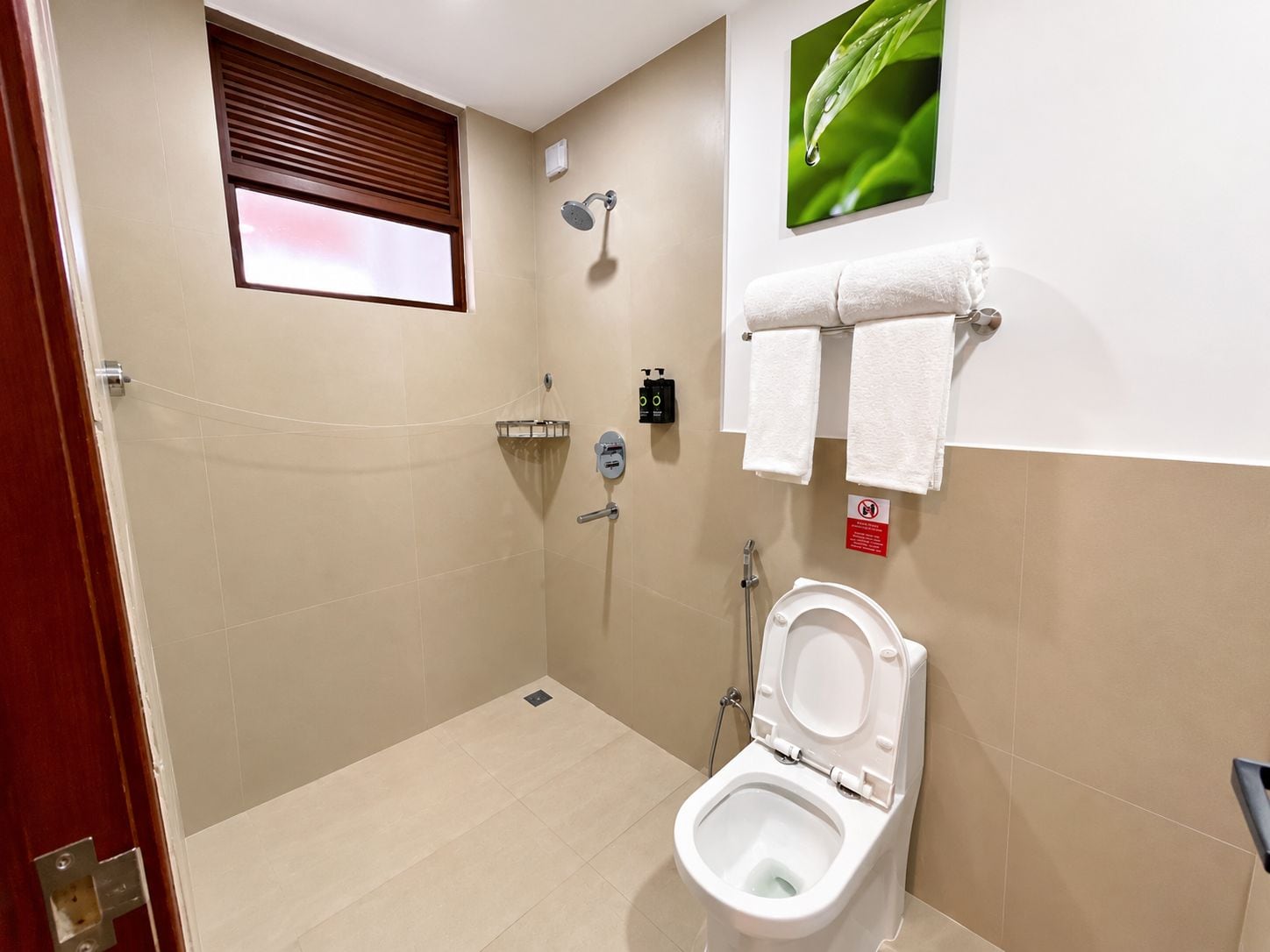 A bathroom with a shower, toilet, and a window.