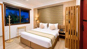 A modern hotel room with a large bed, a ceiling fan, a nightstand with a phone, and a view of the outdoors through a window.