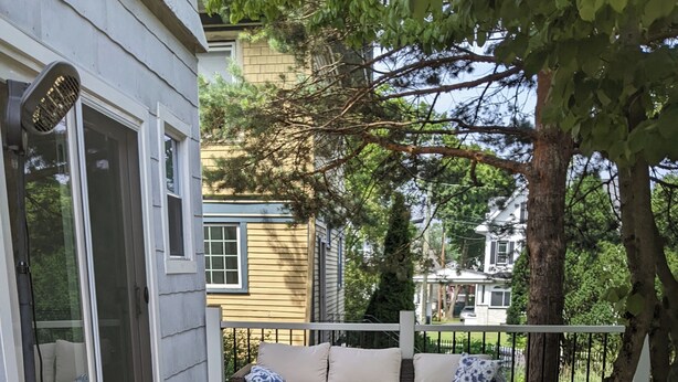A wooden deck with a sofa and ottoman, a covered area with a door, and a railing. - Historic 6-bedroom Retreat in Montclair,NJ- Perfect for Families & Groups! (Montclair Township)