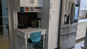 A kitchen with white cabinetry, a stainless steel refrigerator, and a teal office chair. - Historic 6-bedroom Retreat in Montclair,NJ- Perfect for Families & Groups! (Montclair Township)