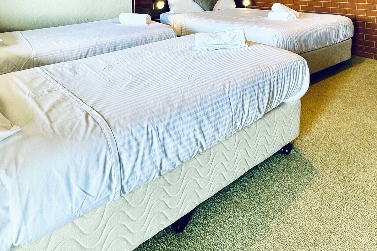 A room with two beds, a brick wall, and a ceiling light.
