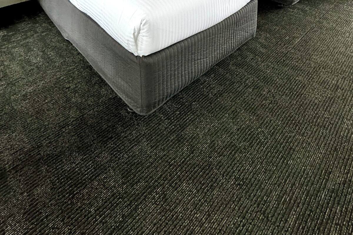 A hotel room with two beds, white walls, a brick-patterned headboard, and a ceiling light.