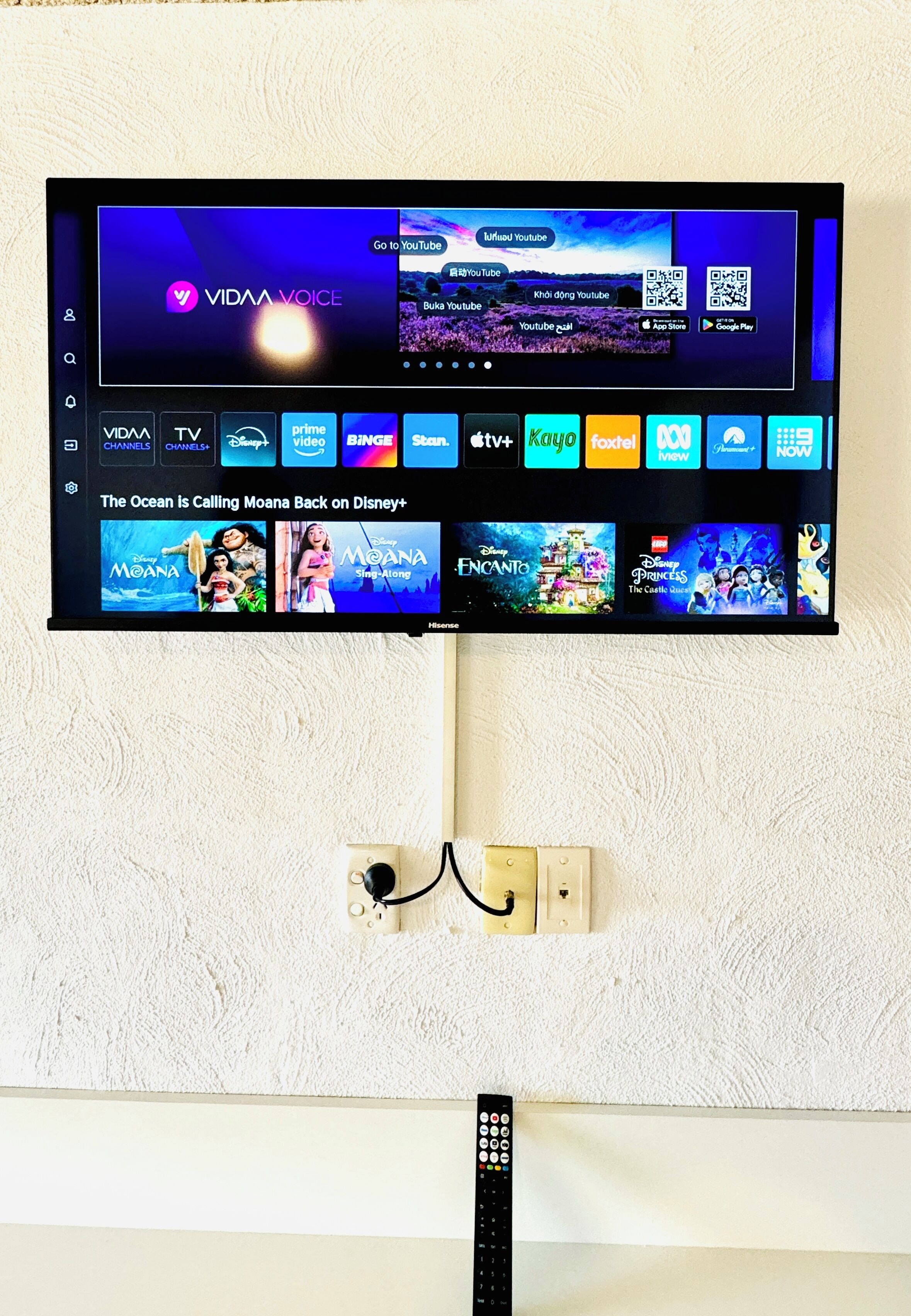 Een flatscreen-televisie bevestigd aan een structuurwand, met een afstandsbediening eronder.