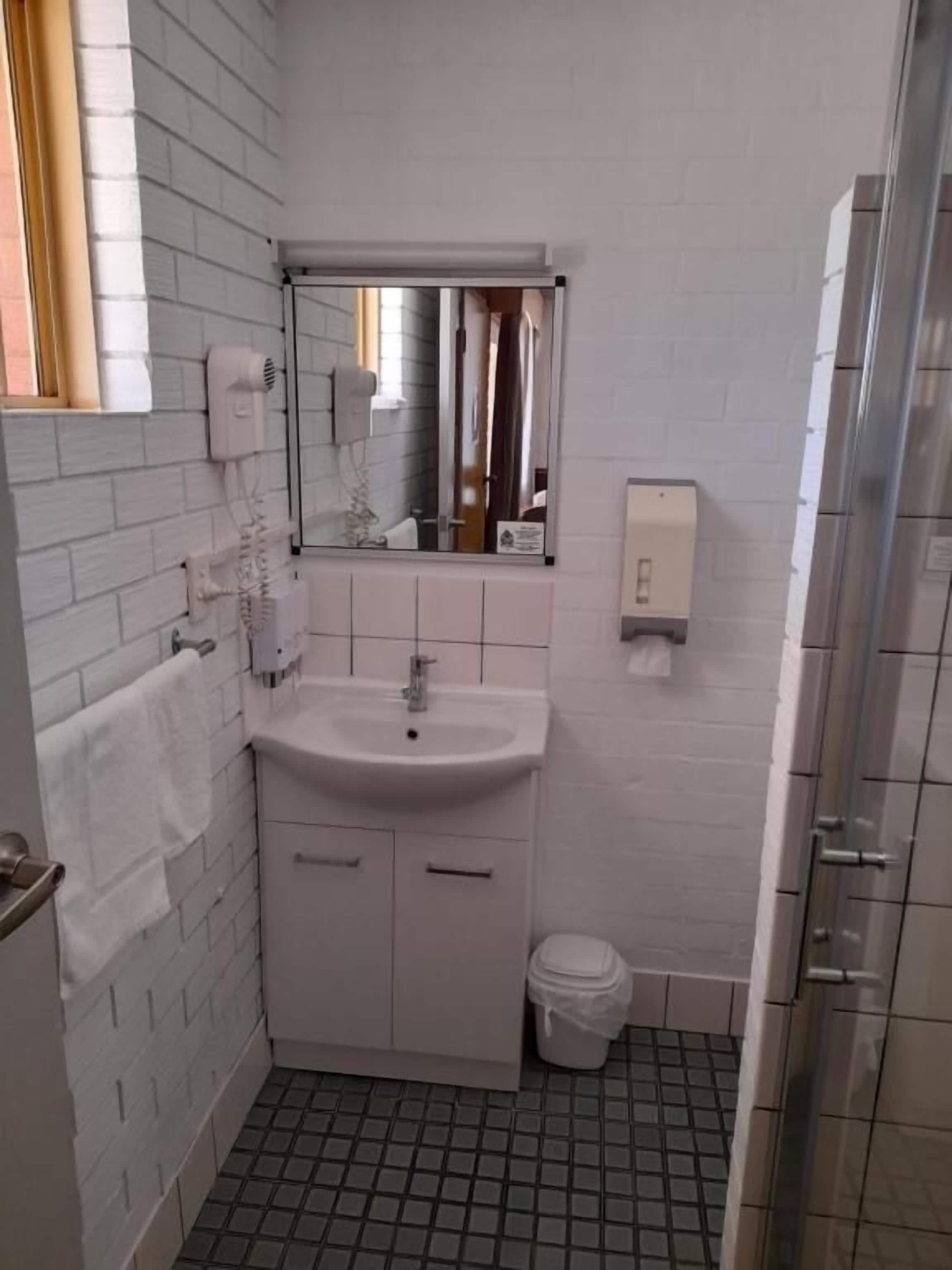 A small, clean bathroom with a white sink, mirror, and tiled floor.