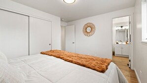 A bedroom with a bed, a white wardrobe, a mirror, and a door leading to a bathroom. - Boise Foothills Boho Haven hosted by Boise BnB! (Boise)