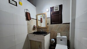 Ένα μικρό, λειτουργικό μπάνιο με νιπτήρα, τουαλέτα και καθρέφτη.