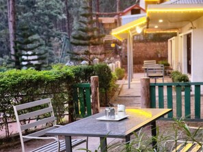A table with a metal kettle and a white cup, surrounded by greenery and a wooden fence. - Pine Valley Resort - PVR Kasauli (Kasauli)