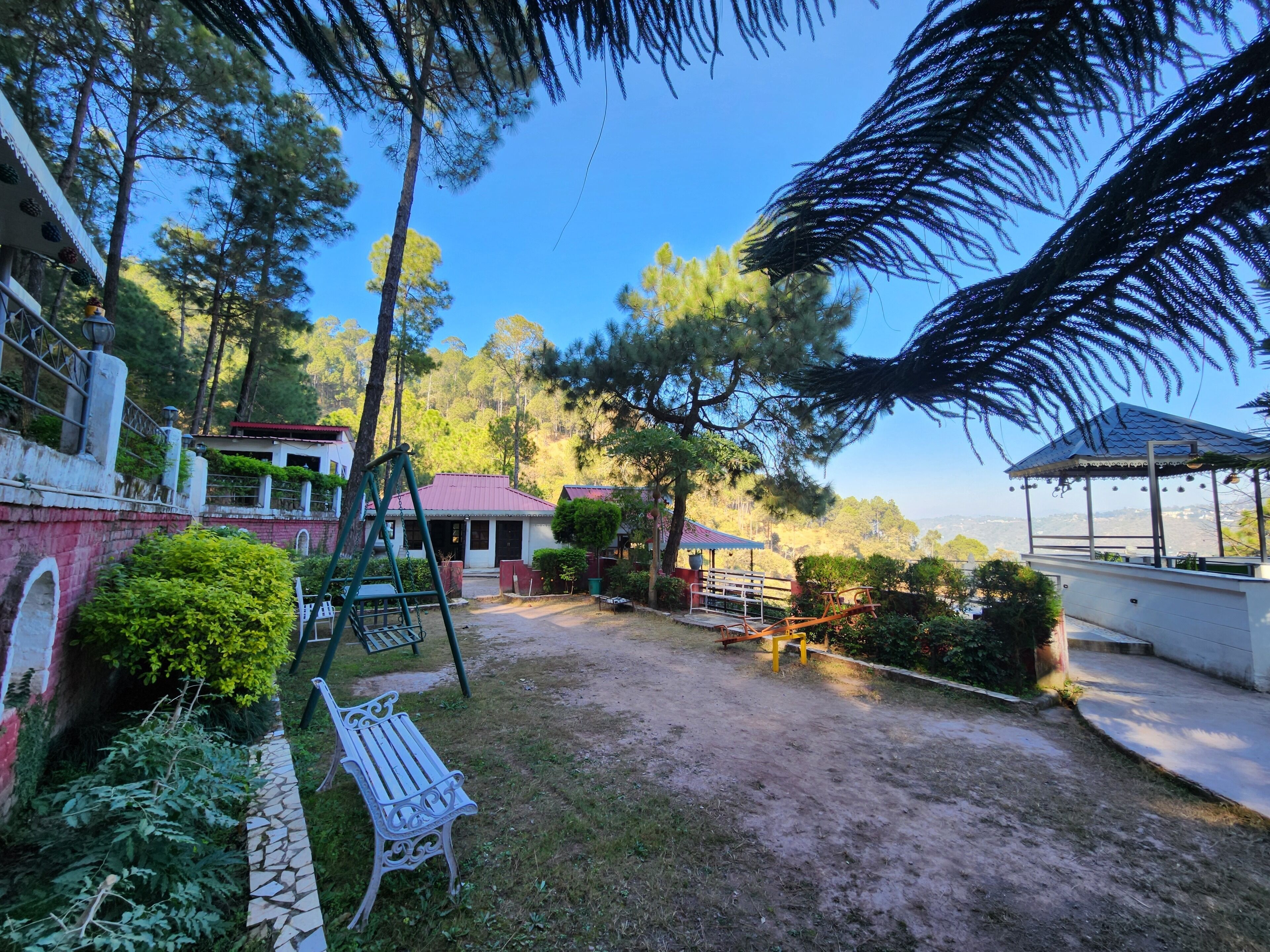 A courtyard with a swing set, a bench, and a gazebo.