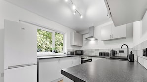 Une cuisine moderne avec des meubles blancs, un plan de travail noir et une fenêtre donnant sur un paysage verdoyant.