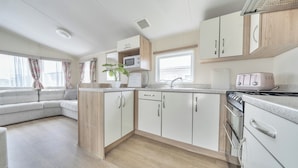 A modern kitchen with white cabinets, a microwave, a toaster, and a stove.