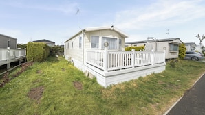A mobile home with a fenced porch, a small deck, and a satellite dish.