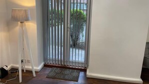 Una habitación con puerta corrediza de vidrio, una lámpara de pie y un felpudo.