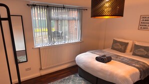 Un dormitorio con cama, una ventana con cortinas, un radiador, una lámpara colgante y un cartel en la pared.