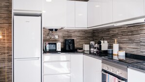 A modern kitchen with white cabinets, a microwave, a coffee maker, and a toaster. - GuestReady - Tranquil Hideaway near Funchal (Funchal)