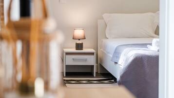 Une chambre d’hôtel bien rangée, avec un lit, une table de chevet dotée d’une lampe et un petit tiroir.