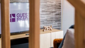 A modern room with a wooden cabinet, a television displaying 'GUEST READY', and a Zen sign on the cabinet. - GuestReady - Tranquil Hideaway near Funchal (Funchal)